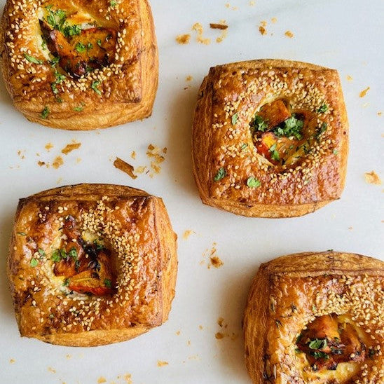 Four golden brown pastries with visible fillings on a light surface.